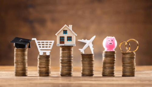 Insurance funding -tycoonstory | tycoonstory media Stacked coins topped with icons of education, shopping, home, travel, savings, and retirement, representing financial goals managed by an insurance company.