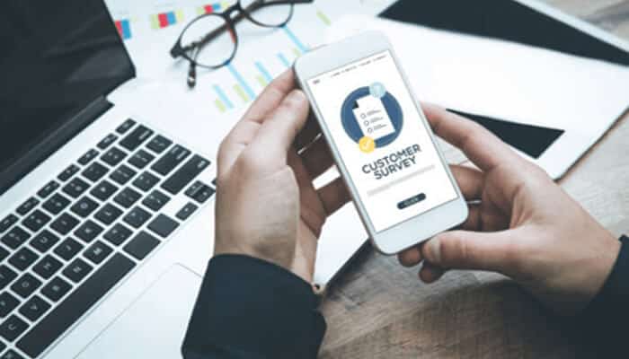 Client surveys | tycoonstory media A person using a mobile phone to complete a customer survey, enhancing workplace productivity by gathering valuable feedback for improvements.