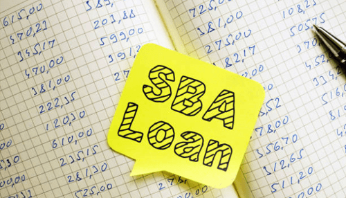 Business loan Sba loan concept displayed on a sticky note over accounting records, representing small business funding and financial planning.