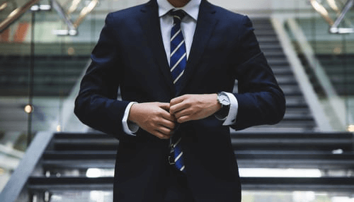 Research your destination-tycoonstory | tycoonstory media A man in a business suit, preparing for a business trip by adjusting his tie and looking sharp for meetings and professional engagements.