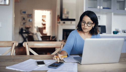 Small family business Woman managing finances and working on a laptop at home, illustrating daily operations and budgeting in a small family business.