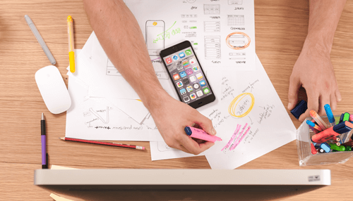 Social media marketing Social media marketing content planning workspace with smartphone, highlighted notes, charts, and creative strategy sketches on a wooden desk.