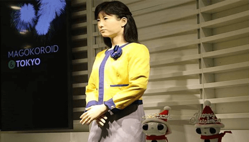 Humanoid robots Female humanoid robot in yellow jacket standing in a presentation room – practical applications of humanoid robots in service industries.