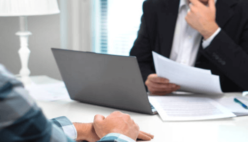 Business loan-tycoonstory | tycoonstory media Business professional reviewing documents with a client in an office, discussing mezzanine debt agreements and funding solutions.