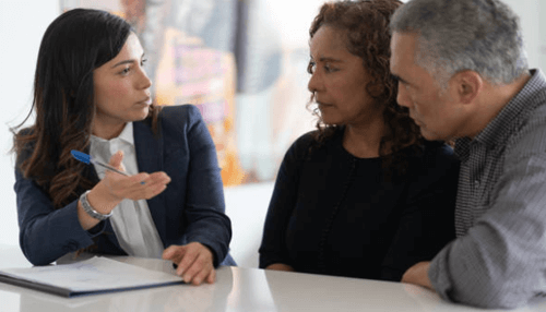 Insurance policy-tycoonstory | tycoonstory media A female insurance agent explaining final expense insurance to a couple, seated across from each other at a table, with a pen in hand.