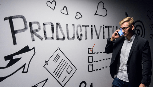 Productivity-tycoonstory | tycoonstory media Freelancer standing in front of a wall with productivity tips written, staying focused on their tasks and managing time effectively