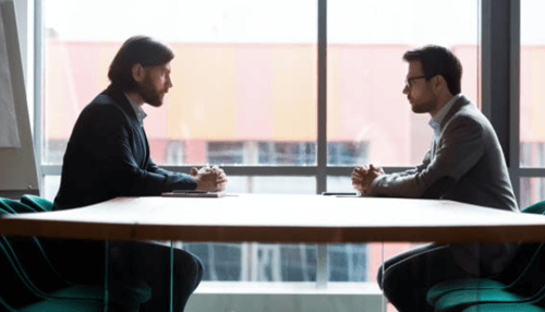 Disadvantages of a joint venture-tycoonstory | tycoonstory media Two business professionals discussing a joint venture agreement across a meeting table.