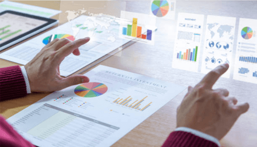 Expand business A person analyzing financial charts and colorful graphs on both paper and digital screens to review investment performance.