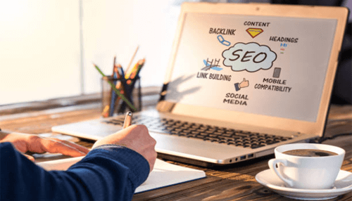 Seo Reputation crisis: a person writing notes while viewing a laptop screen with an seo strategy diagram, including keywords like'Backlink,' 'Content,' 'Link Building,' and 'Mobile Compatibility.