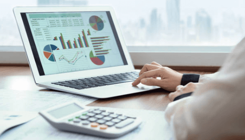 Use payroll software-tycoonstory | tycoonstory media Hands analyzing charts on a laptop next to a calculator, essential tools for managing payroll and finance.