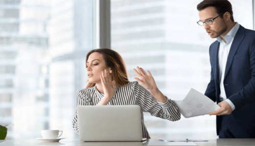 Avoid fighting with your boss-tycoonstory | tycoonstory media Supervisor leaning over an employee at a laptop with paperwork, showing micromanagement behaviour that disrupts productivity