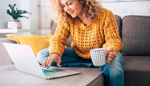 Promoting positive content-tycoonstory | tycoonstory media Reputation crisis: a relaxed woman sitting on a sofa, sipping a coffee while working on her laptop, symbolizing a calm work-from-home environment.