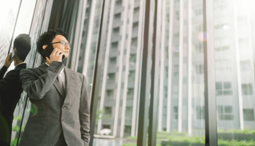 Real estate entrepreneurs A professional standing by a glass building while talking on the phone, representing real estate business and corporate property dealings.