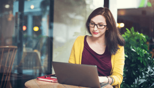 Identify primary users-tycoonstory | tycoonstory media A woman working on her laptop in a coffee shop, possibly designing or updating her website to enhance user experience and engagement