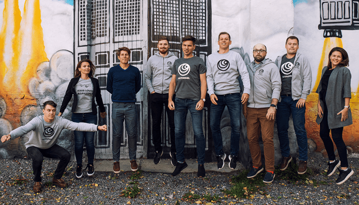 Outfunnel Outfunnel team group photo: the entire outfunnel team posing together in front of a mural, all wearing matching outfunnel-branded apparel, displaying a sense of unity and collaboration.