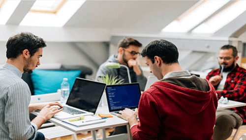 Startup incubator A group of professionals working on laptops in a co-working space, reflecting the collaborative environment of a startup incubator that fosters innovation and teamwork.
