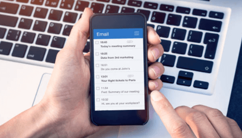 Writing marketing emails-tycoonstory | tycoonstory media Person checking marketing emails on a smartphone, with an email inbox open on the screen