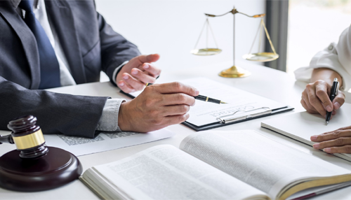 How debt lawyer's Services Can be Beneficial A debt settlement lawyer discussing legal matters with a client, with legal scales and books on the desk, representing the negotiation process for debt resolution
