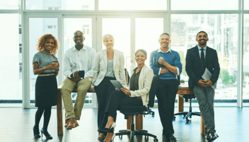 How to compensate employees A diverse group of professionals standing together in an office, symbolizing the value of compensate employees to boost morale and team collaboration.