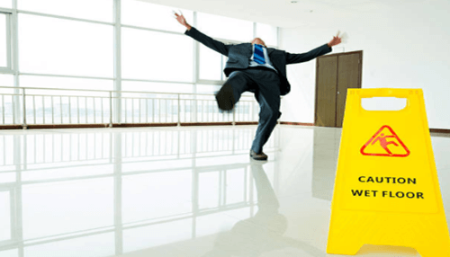 Slip-and-fall faqs Person slipping on a wet floor near a caution sign, highlighting slip-and-fall accident hazards and property owner liability.