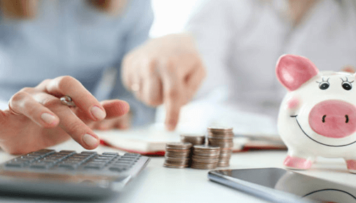 Tips on how to save income tax Tax benefits concept shown through budgeting calculations, coin stacks, and a piggy bank symbolizing smart tax savings and financial planning