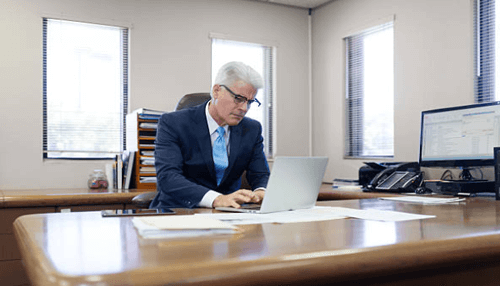 Handles the task of cash management Professional in a business suit working on a laptop in an office, symbolizing the efficient management of financial operations and cash flow in a corporate environment.