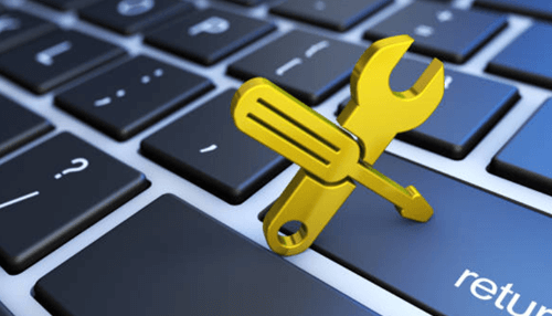 Free business tools for startups An image of a keyboard with a golden screwdriver and wrench placed over the'Return' key, symbolizing essential business tools for startups.