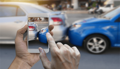 Pictures of the accident Hands photographing a rear-end vehicle collision using a smartphone, documenting damage often seen after a truck accident.