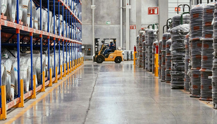 Stages of order fulfillment -tycoonstory | tycoonstory media A warehouse with inventory shelves and a forklift moving items, showcasing the storage aspect of the order fulfillment process.