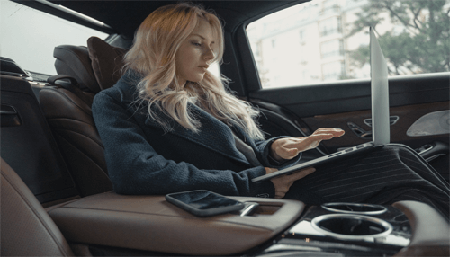 Manage your on-site driving needs-tycoonstory (1) | tycoonstory media Businesswoman working on a laptop inside a luxury car while preparing for her next business trip.