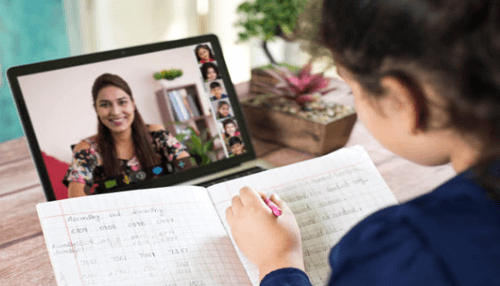 Technology related business ideas A student participating in an online class, writing in a notebook, highlighting the growing trend of technology-related businesses in the education sector.