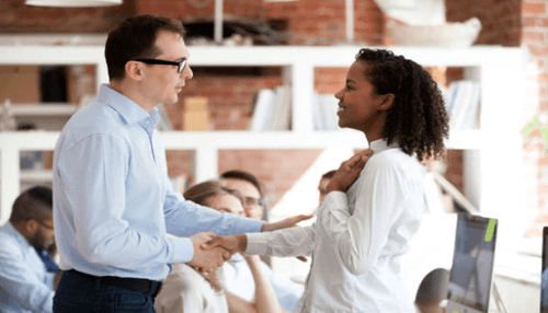 Recruit good candidates A manager shaking hands with a smiling team member in an office, symbolizing successful hiring and choosing the right employee for the role.