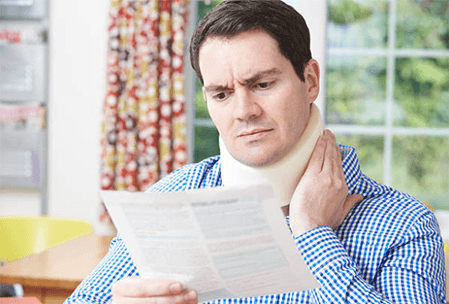 A man with a neck brace reviewing paperwork, emphasizing the process of handling whiplash claims and seeking proper compensation.