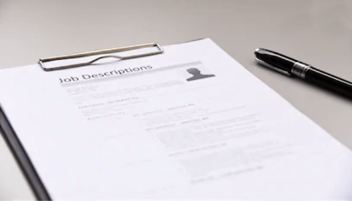 Writing a great job description A job description document on a clipboard with a pen beside it, symbolizing the process of job recruiting and preparing job listings.
