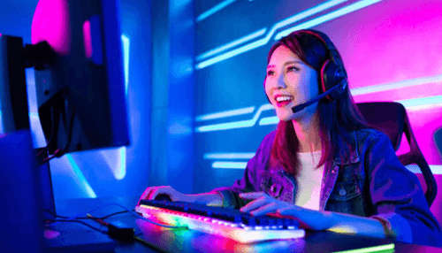 Start watching esports games - tycoonstory | tycoonstory media A female gamer wearing a headset enjoying an online esports game on a colorful rgb-lit gaming setup.