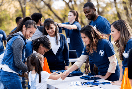 Ways to make your business more socially conscious-tycoonstory | tycoonstory media A group of diverse hands, some in business attire, coming together to cradle and protect a small, green seedling growing in soil. This represents a socially responsible commitment to sustainability, growth, and environmental care.
