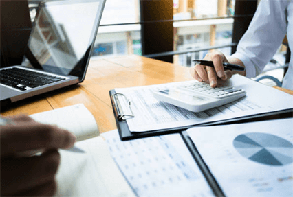 Financial management tips for startups-tycoonstory | tycoonstory media A close-up view of business professionals analyzing printed bar charts and pie graphs on a table next to a laptop, focusing on sales performance and data trends.