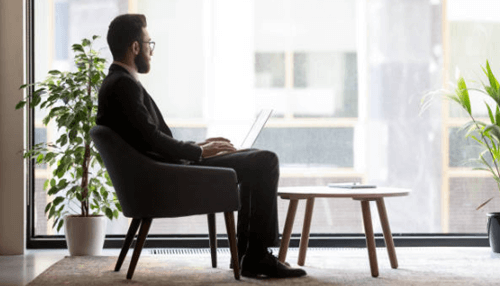 Become a business mogul A determined entrepreneur sitting in a modern, sunlit office lounge with a laptop, representing the focus and dedication required to become a business mogul.