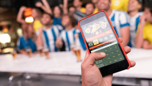 12bet for mobile -tycoonstory | tycoonstory media Person using a sports betting app on a smartphone with a cheering crowd in the background, illustrating live sports wagering experiences offered by platforms such as 12bet.