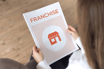 Franchises A person holding a franchise brochure, showcasing the opportunity for owning and investing in franchises