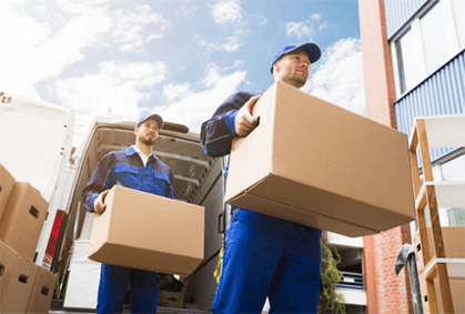 Diy moving-tycoonstory | tycoonstory media Workers carrying boxes from a moving truck as part of a move by your own process, showcasing the physical labor involved in self-moving tasks