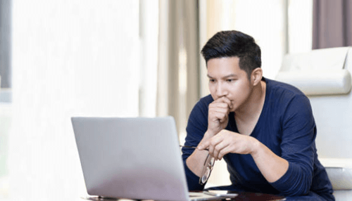 Planning your funds A focused young man researching on a laptop at home, preparing for starting a business.