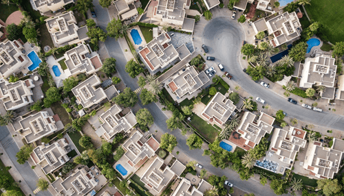 Invest in real estate Aerial view of a residential neighborhood with houses, streets, and swimming pools, showcasing real estate properties.