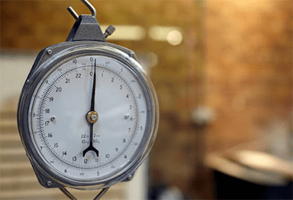 Hanging scale-tycoonstory | tycoonstory media Industrial scales: vintage hanging scale with a white dial and black markings a close-up the best for very precise weight measurement.