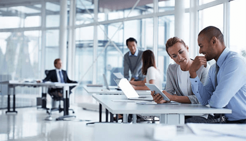 Working out of a proper office space - tycoonstory | tycoonstory media Team of professionals collaborating in a modern office space with laptops and digital devices.