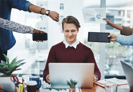Delegating "young professional working on a laptop while being handed mobile phones and documents, symbolizing multitasking and managing multiple tasks in a modern office.