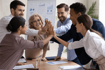 Invest in a proper team A diverse team of professionals smiling and joining hands for a high-five during a successful meeting in an office setting.