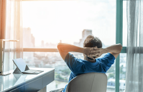 Startup Startup founder relaxing at a desk while planning future business growth with a laptop overlooking the city skyline.