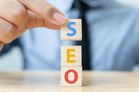 Seo-tycoonstory | tycoonstory media A person stacking blocks with the letters s-e-o, representing the concept of search engine optimization.