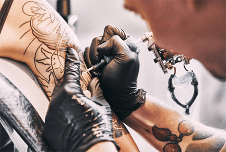 Best tattoo needles-tycoonstory | tycoonstory media A tattoo artist working on a clients arm, using a tattoo machine with a specific needle types of needles to create intricate designs.